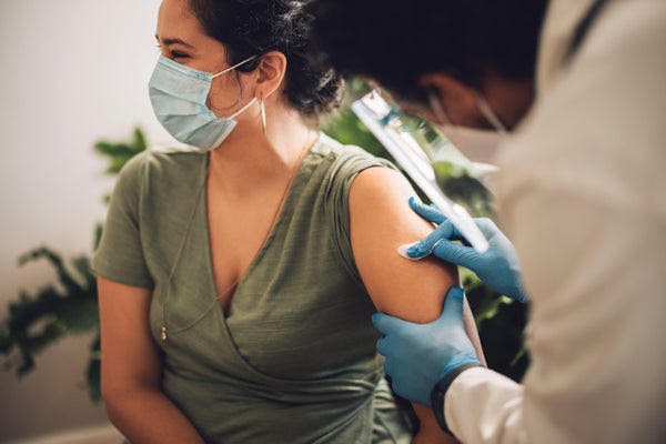 Doctor prepping a woman's arm with alcohol swab prior to administering vaccination injection