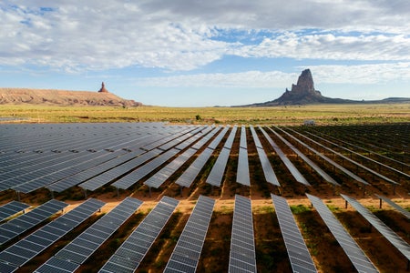 Aerial view of a solar plant in Navajo land with Monuments in background.