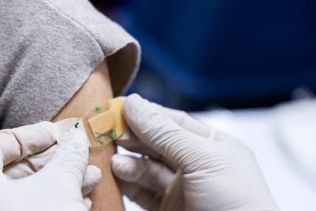 White gloved doc adding bandaid to child's arm.
