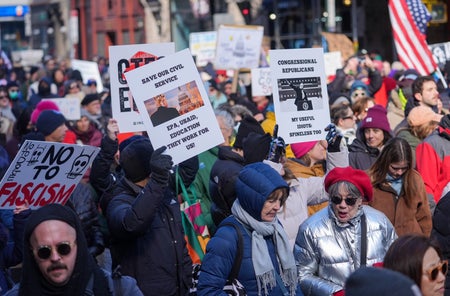 Protesters gather at 'Stop the Coup' rally holding signs.