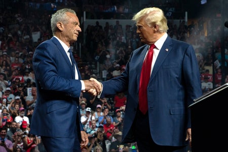 Former presidential candidate Robert F. Kennedy Jr. and President-elect Donald Trump shaking hands on stage at a campaign rally