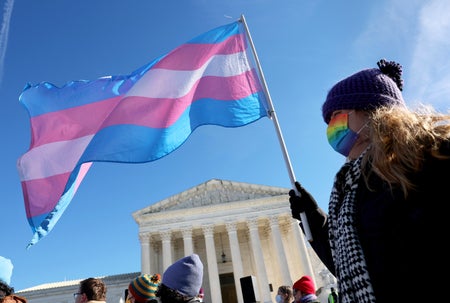 A transgender rights supporter holds the transgender flag while attending a rally outside of the U.S. Supreme Court as the high court hears arguments in a case on transgender health rights on December 04, 2024 in Washingt