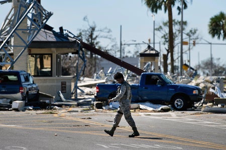 A military police officer walks in the street in front of a large amount of debris at the destroyed gate of Tyndall Air Force Base, in Florida in the aftermath of Hurricane Michael on October 12, 2018
